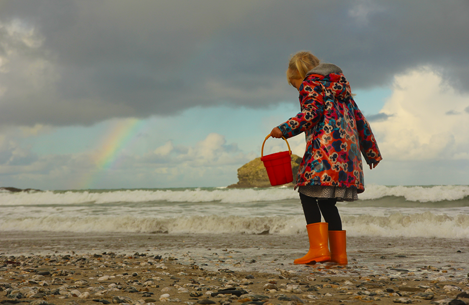 Child on beach with rainbow
