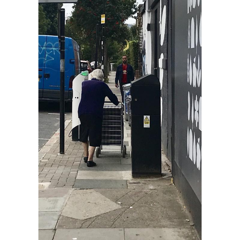 Elderly lady weaving through street clutter