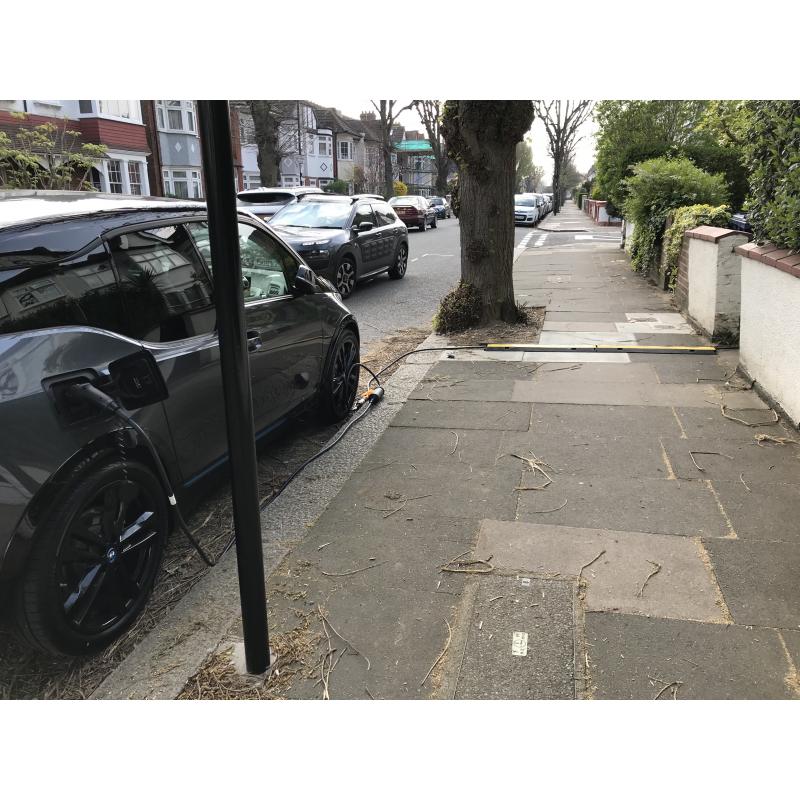 An electric car obstructing the footway with its charging cable